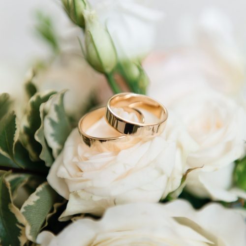 Wedding engagement rings and flowers wedding bouquet background, selective focus, macro